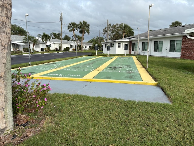 view of home's community with shuffleboard and a yard