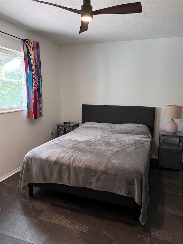 bedroom featuring a ceiling fan, baseboards, and a textured ceiling