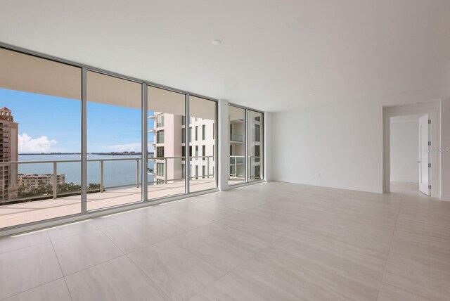 301 Quay Commons Unit 1111, Sarasota, FL 34236 - unfurnished room featuring a water view, expansive windows, and tile patterned flooring