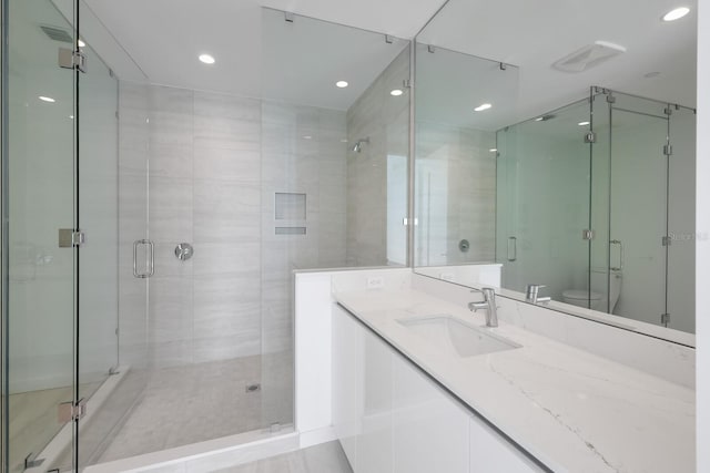 bathroom featuring vanity, toilet, and a shower with shower door