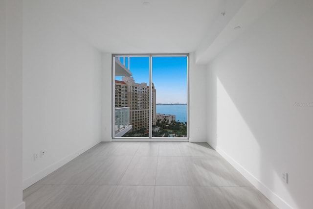 spare room with expansive windows and a water view