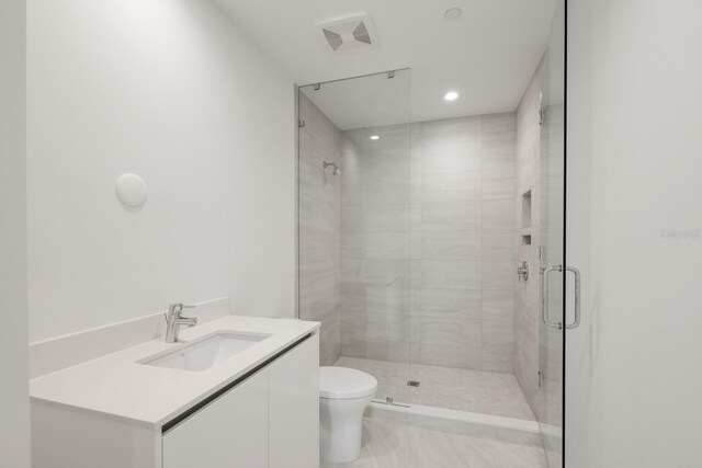 301 Quay Commons Unit 1111, Sarasota, FL 34236 - bathroom featuring a shower stall, toilet, vanity, and recessed lighting