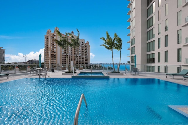 view of pool with a water view, a hot tub, and a patio area