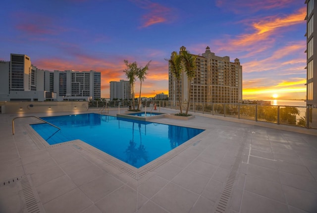 pool at dusk featuring a patio