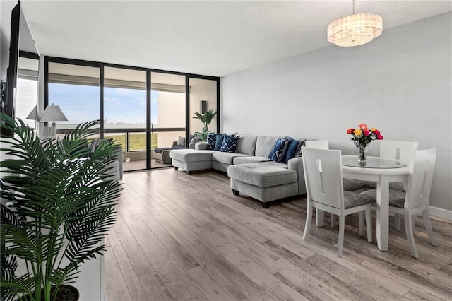 living room featuring expansive windows, light wood-type flooring, and an inviting chandelier