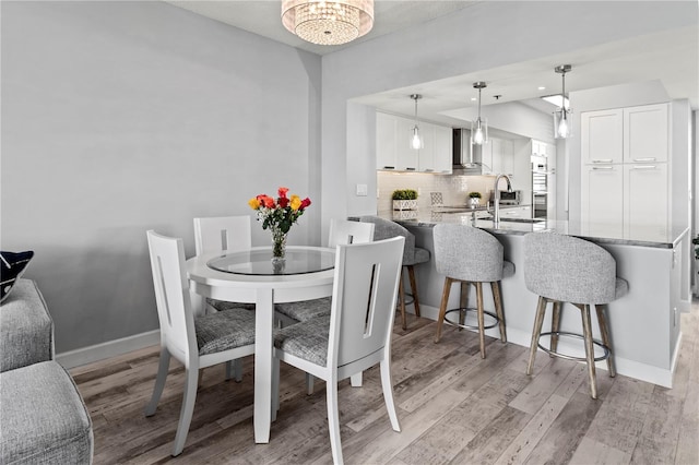 dining room with light hardwood / wood-style flooring, an inviting chandelier, and sink