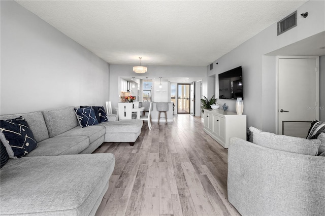 living room with a textured ceiling and light wood-type flooring