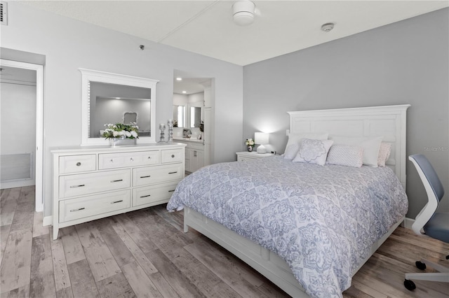 bedroom with ensuite bathroom, light hardwood / wood-style flooring, and ceiling fan