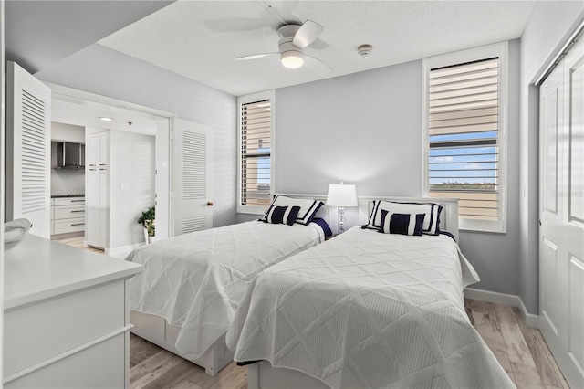 bedroom with ceiling fan, a textured ceiling, and light wood-type flooring