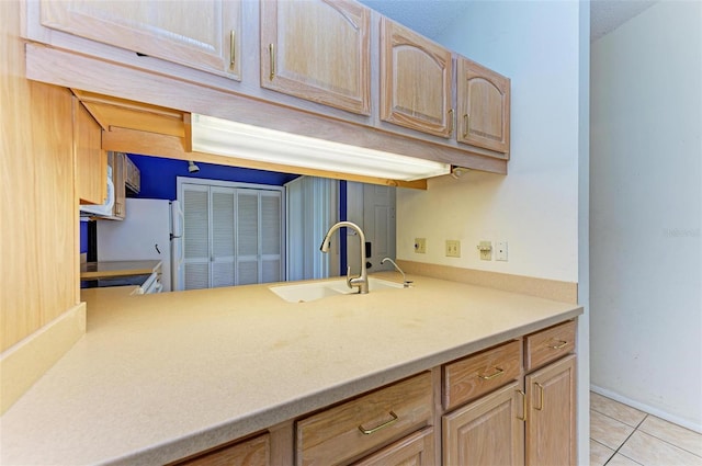 kitchen with light brown cabinets, white refrigerator, light tile patterned floors, and sink