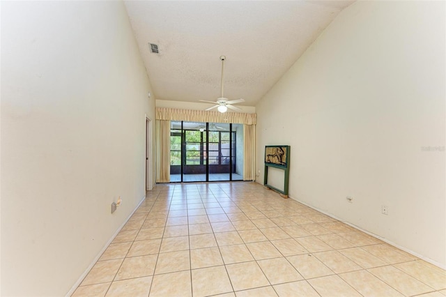 empty room featuring light tile patterned floors, a textured ceiling, high vaulted ceiling, and ceiling fan