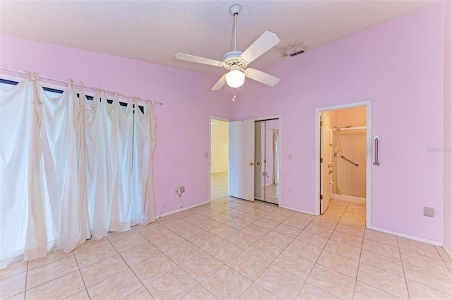 unfurnished bedroom featuring light tile patterned floors, a textured ceiling, ensuite bathroom, and ceiling fan