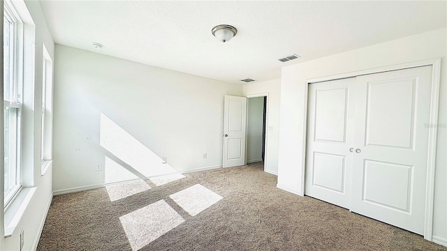 unfurnished bedroom with a textured ceiling, carpet floors, and a closet