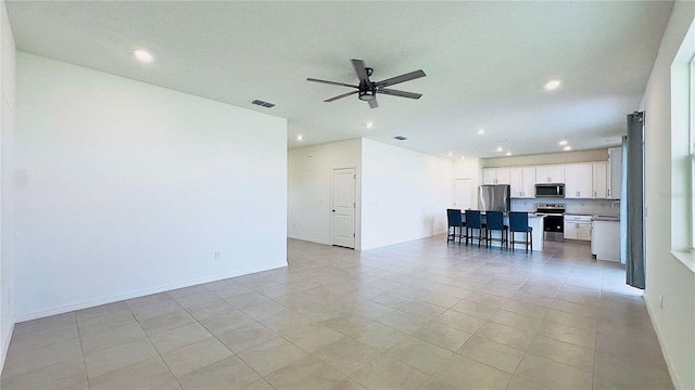 unfurnished living room featuring ceiling fan, sink, and light tile patterned floors