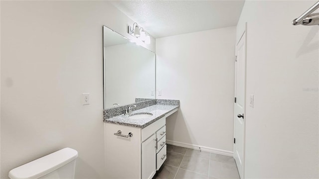 bathroom with tile patterned flooring, vanity, toilet, and a textured ceiling