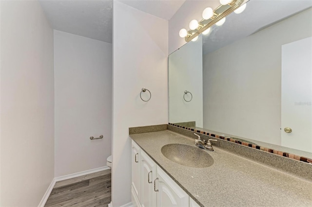 bathroom featuring wood-type flooring, vanity, and toilet