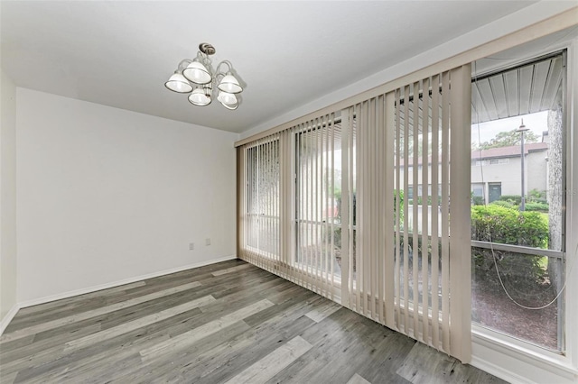 unfurnished dining area with wood-type flooring and an inviting chandelier