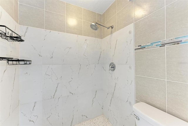 bathroom with a tile shower and toilet