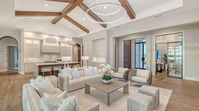 living room with vaulted ceiling with beams and light hardwood / wood-style floors