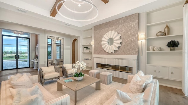 living room with a tray ceiling, built in features, light hardwood / wood-style floors, and french doors