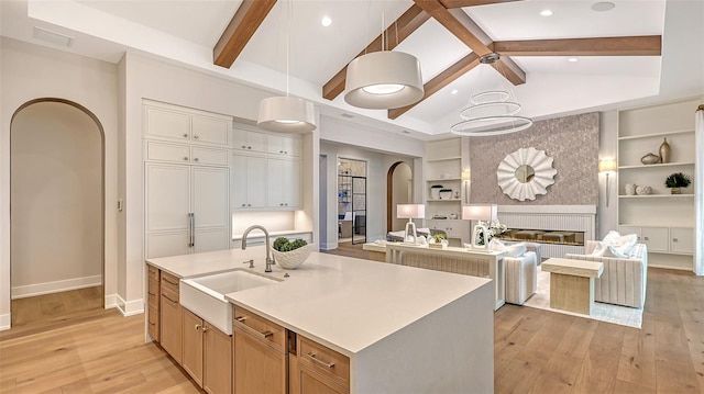 kitchen with a large island, sink, light hardwood / wood-style floors, and decorative light fixtures