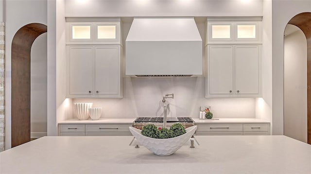 kitchen with white cabinets, an island with sink, and custom range hood