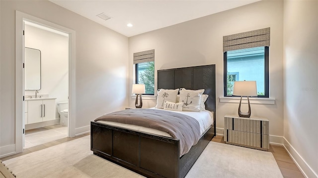 bedroom featuring light hardwood / wood-style floors, sink, and connected bathroom