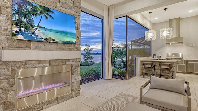 sunroom with a notable chandelier, a stone fireplace, and sink