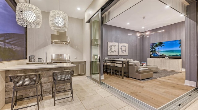 interior space with sink, exhaust hood, light hardwood / wood-style flooring, a notable chandelier, and hanging light fixtures