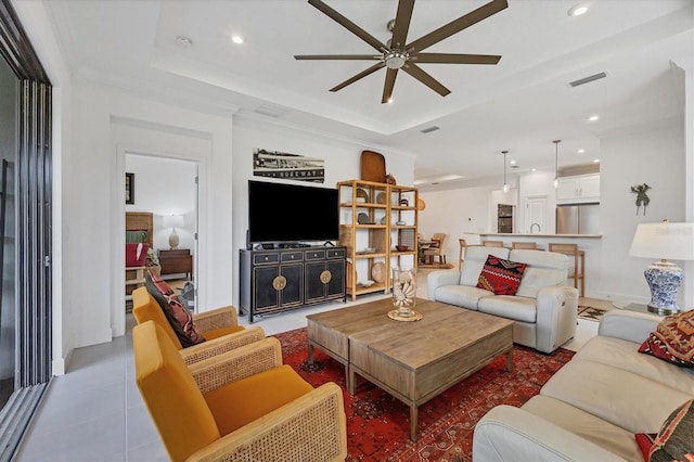 tiled living room with a tray ceiling, ceiling fan, and crown molding