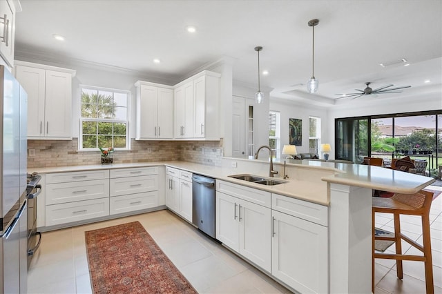 kitchen featuring a kitchen breakfast bar, stainless steel dishwasher, sink, pendant lighting, and white cabinetry