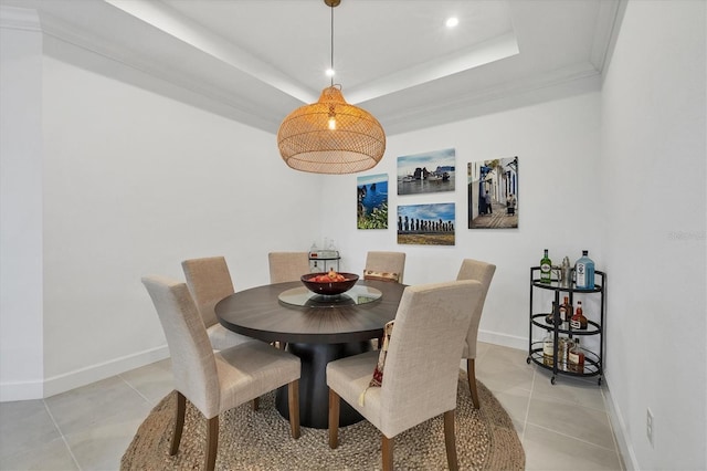 dining space featuring a tray ceiling, crown molding, and light tile patterned flooring