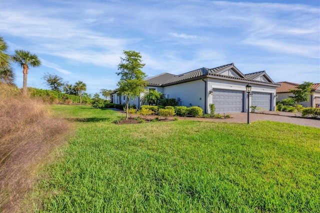 view of front facade featuring an attached garage, driveway, a front lawn, stucco siding, and a tile roof