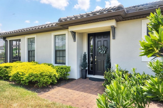 view of exterior entry featuring stucco siding and a tile roof
