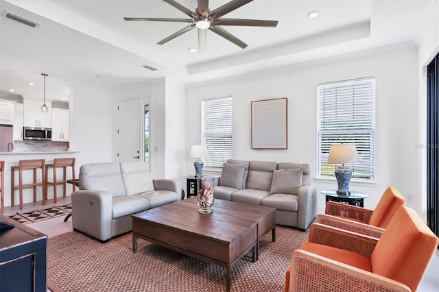 living room with a ceiling fan, recessed lighting, and a raised ceiling
