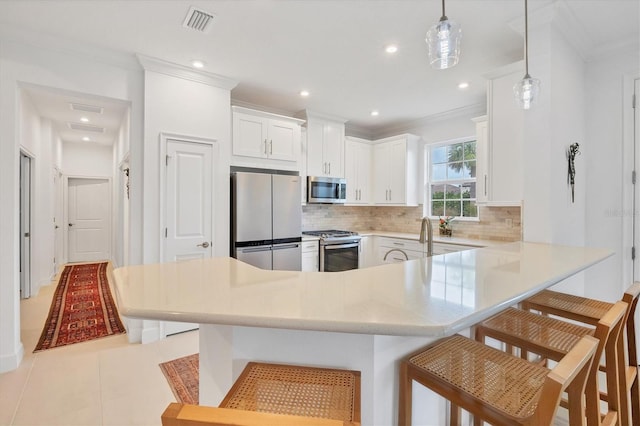 kitchen featuring stainless steel appliances, tasteful backsplash, a breakfast bar, a peninsula, and light countertops