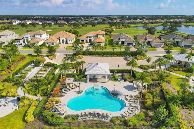 aerial perspective of suburban area featuring a pool and a nearby body of water