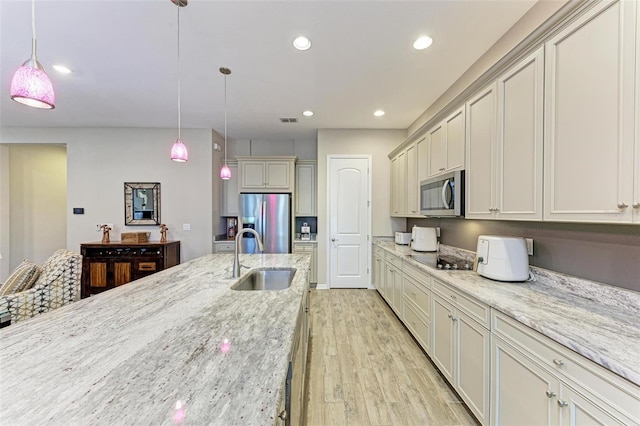 kitchen featuring light stone counters, sink, hanging light fixtures, and appliances with stainless steel finishes