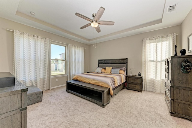 carpeted bedroom with ceiling fan and a tray ceiling