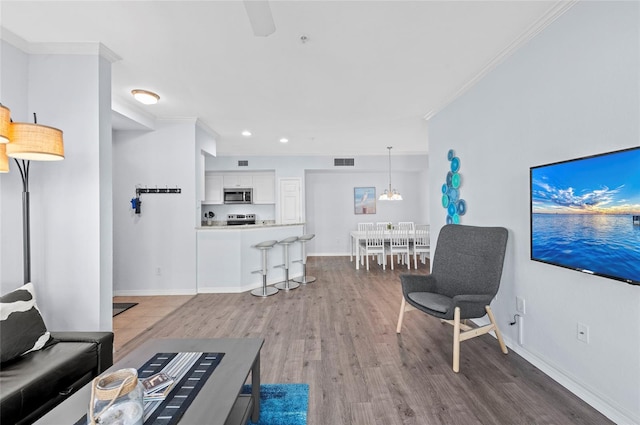 living room featuring wood-type flooring, an inviting chandelier, and ornamental molding