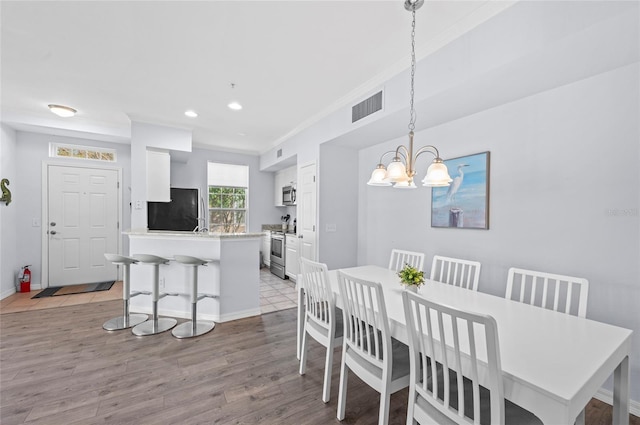 dining space featuring a chandelier, light hardwood / wood-style floors, and ornamental molding