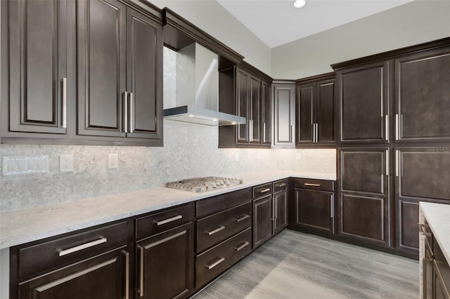 kitchen with decorative backsplash, light wood-type flooring, wall chimney range hood, and stainless steel gas stovetop