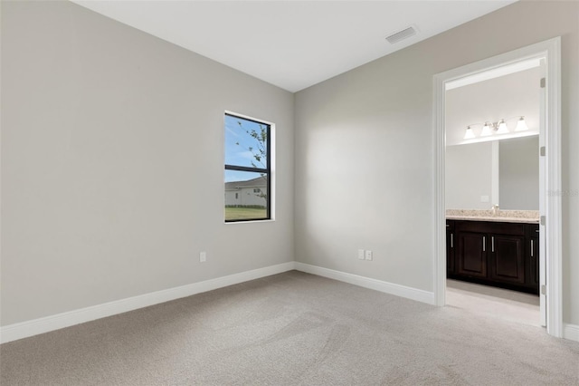 unfurnished bedroom featuring light colored carpet and ensuite bath