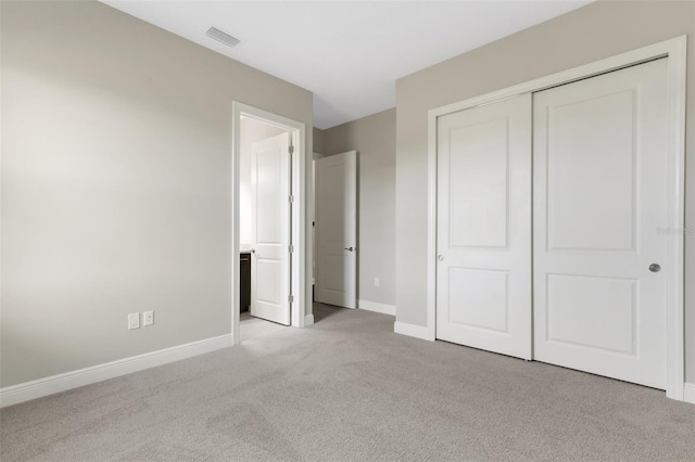 unfurnished bedroom with light carpet and a closet