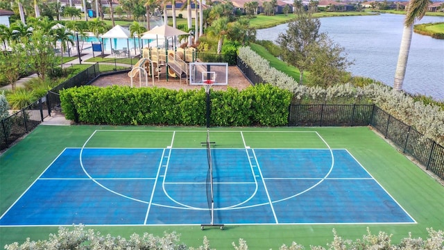 view of basketball court featuring a playground and a water view