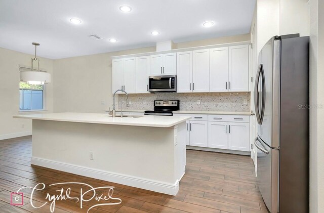 kitchen featuring pendant lighting, stainless steel appliances, white cabinetry, and sink