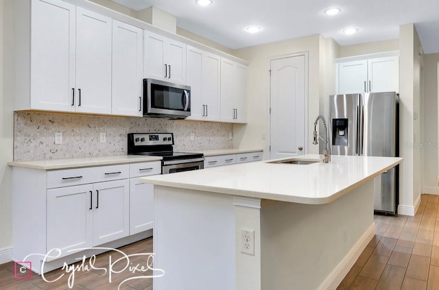 kitchen featuring white cabinets, an island with sink, stainless steel appliances, and light wood-type flooring