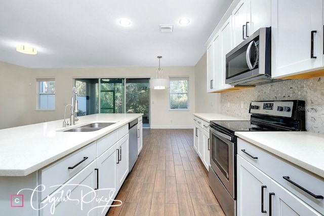 kitchen with pendant lighting, white cabinets, sink, dark hardwood / wood-style floors, and appliances with stainless steel finishes