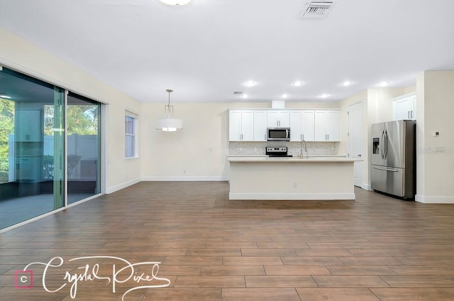 kitchen featuring dark hardwood / wood-style flooring, white cabinets, pendant lighting, and appliances with stainless steel finishes