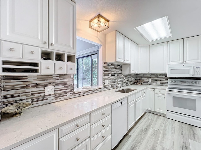 kitchen featuring white appliances, white cabinets, sink, light hardwood / wood-style floors, and light stone counters